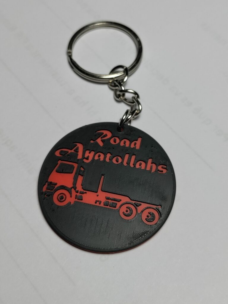 Clauer 3D negre i vermell amb el text Road Ayatollahs i la silueta d'un camió portacontenidors