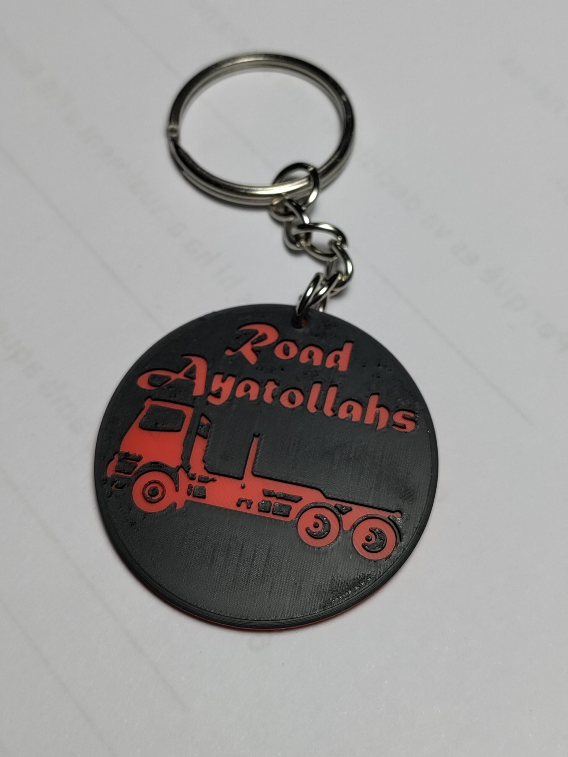 Clauer 3D negre i vermell amb el text Road Ayatollahs i la silueta d'un camió portacontenidors